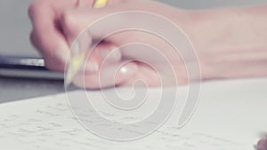 Woman's hands writing with a pencil and typing on a calculator