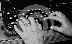 Woman`s hands writing on a vintage typewriter. Hands writing on old typewriter black and white photo