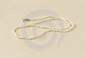 Woman`s Jewelry. Vintage jewelry background. Beautiful pearl necklace on cream background. Flat lay, closeup