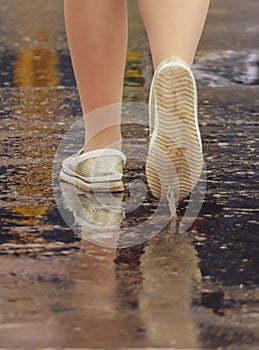 Woman`s legs crossing the road in the rain