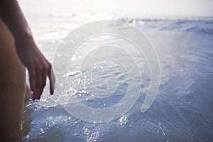 Woman`s legs and hand standing looking at ocean