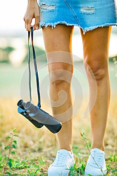 Woman`s legs and hanging binoculars