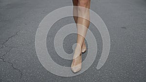 Woman`s legs in high heel shoes walking on road slow motion.