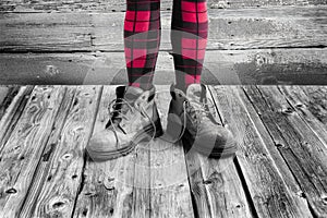 Woman`s legs from knees down wearing red and black tights and big boots