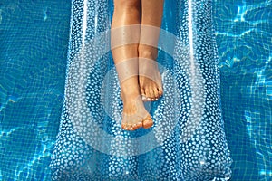 Woman's legs on lilo in pool