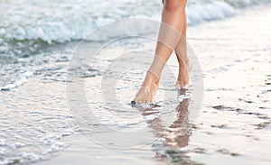 woman`s legs near the sea on the sand. Beautiful legs of a slender girl. A sports women`s legs.