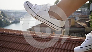 Woman`s legs in shoes above roofs