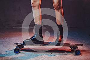 Woman`s legs on skateboard in dark background with lights