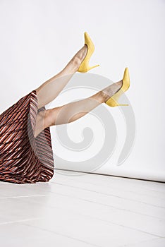 Woman`s legs up in the air with yellow high heeled shoes.