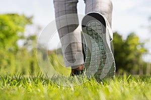 Woman`s legs wear sports shoes, Jogging on the green grass in the park at morning, Healthy lifestyle concept