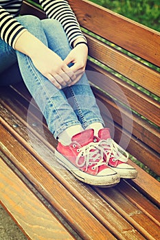 Woman`s legs wearing red canvas sneakers