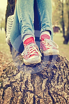 Woman`s legs wearing red canvas sneakers