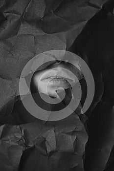 Woman`s mouth n hole in black crumpled paper background, black and white concept photography for blog or poster