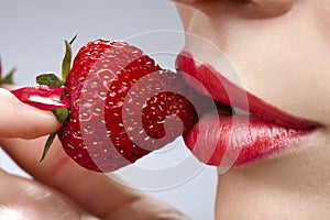 Woman`s mouth with red strawberry photo