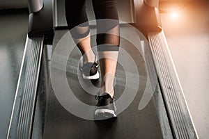 Woman`s muscular legs on treadmill