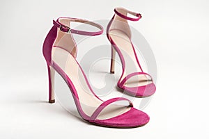 Woman`s pink high heels shoes with ankle strap on a white background.