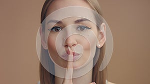 Woman`s portrait makes shhhh with a finger