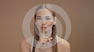 Woman`s portrait makes shhhh with a finger