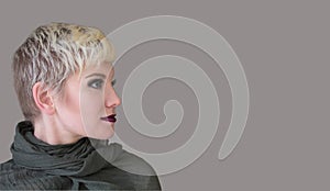 Woman`s profile portrait blonde. Fashion hairstyle, haircut, makeup in grey shades.