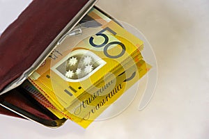 A woman`s red purse filled with Australian fifty dollar notes.