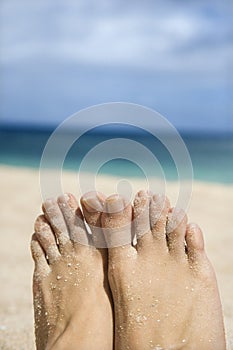 Woman's sandy feet on beach.