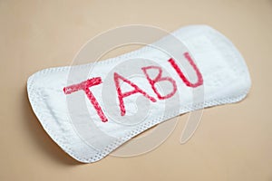 Woman's sanitary pad with word tabu. Abstract social concept of fear of talking about menstrual period