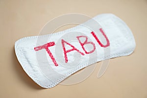 Woman's sanitary pad with word tabu. Abstract social concept of fear of talking about menstrual period photo