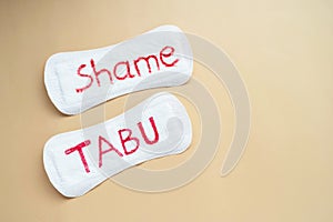 Woman's sanitary pad with word tabu and shame. Abstract social concept of shaming women for their menstruation photo
