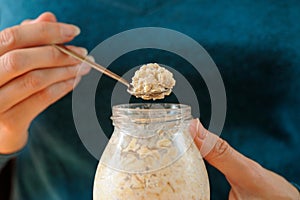 Woman's slender hands holding glass jar and spoon with overnight