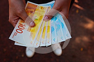 Woman`s two hands holding a fan of money of Israeli New Shekels