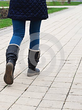 A woman`s walk in autumn boots on the sidewalk in the park