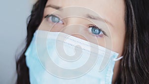 Woman with sad blue eyes in protective face mask, sadness, grief, stress and negative emotion during quarantine lockdown