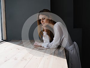 woman with sad facial expression white dress near luxury window