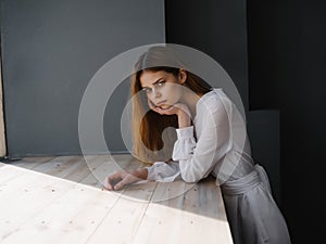 woman with sad facial expression white dress near luxury window