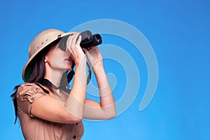 Woman in safari hat searching with binoculars