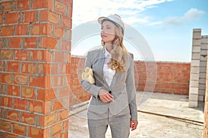 Woman in safety helmet with drawings at construction