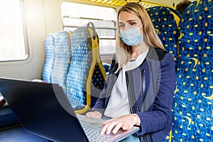 woman with safety mask using laptop in public transport. covid-19 pandemic