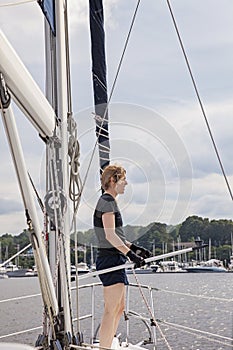 Woman on sailboat with boat hook preparing to dock boat