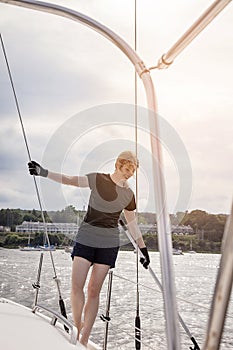 Woman on sailboat with boat hook preparing to dock boat