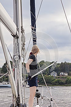 Woman on sailboat with boat hook preparing to dock boat