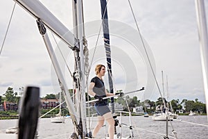 Woman on sailboat with boat hook preparing to dock boat