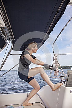 Woman sailing pulling ropes to adjust sails on sailboat