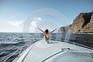 Woman sailing on the yacht near the rocky coast