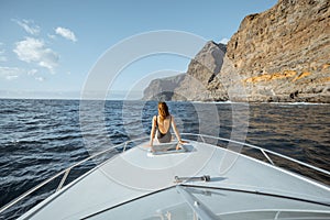 Woman sailing on the yacht near the rocky coast