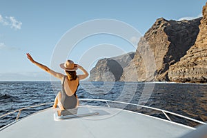 Woman sailing on the yacht near the rocky coast