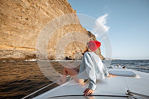 Woman sailing on the yacht near the rocky coast