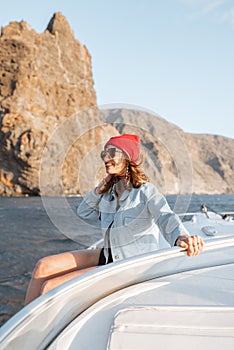 Woman sailing on the yacht near the rocky coast