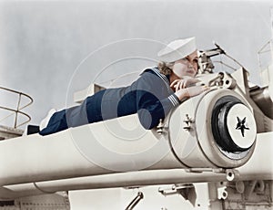 Woman in a sailors uniform lying on a cannon