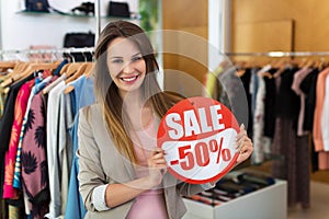 Woman with sale sign in clothes shop