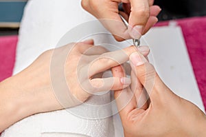 Woman in salon receiving manicure by nail beautician photo